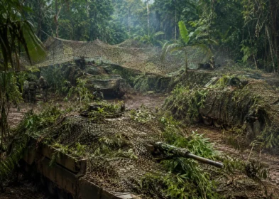 Armored vehicles concealed under jungle camouflage nets during a field exercise