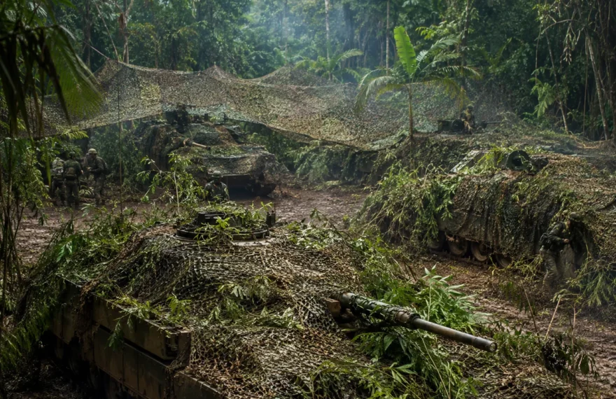 Armored vehicles concealed under jungle camouflage nets during a field exercise