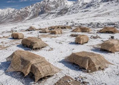 High-altitude army field camp concealed with snow and desert camouflage nets