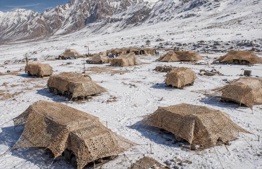 High-altitude army field camp concealed with snow and desert camouflage nets