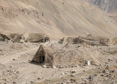 Highland desert field camp concealed with terrain-colored camouflage nets