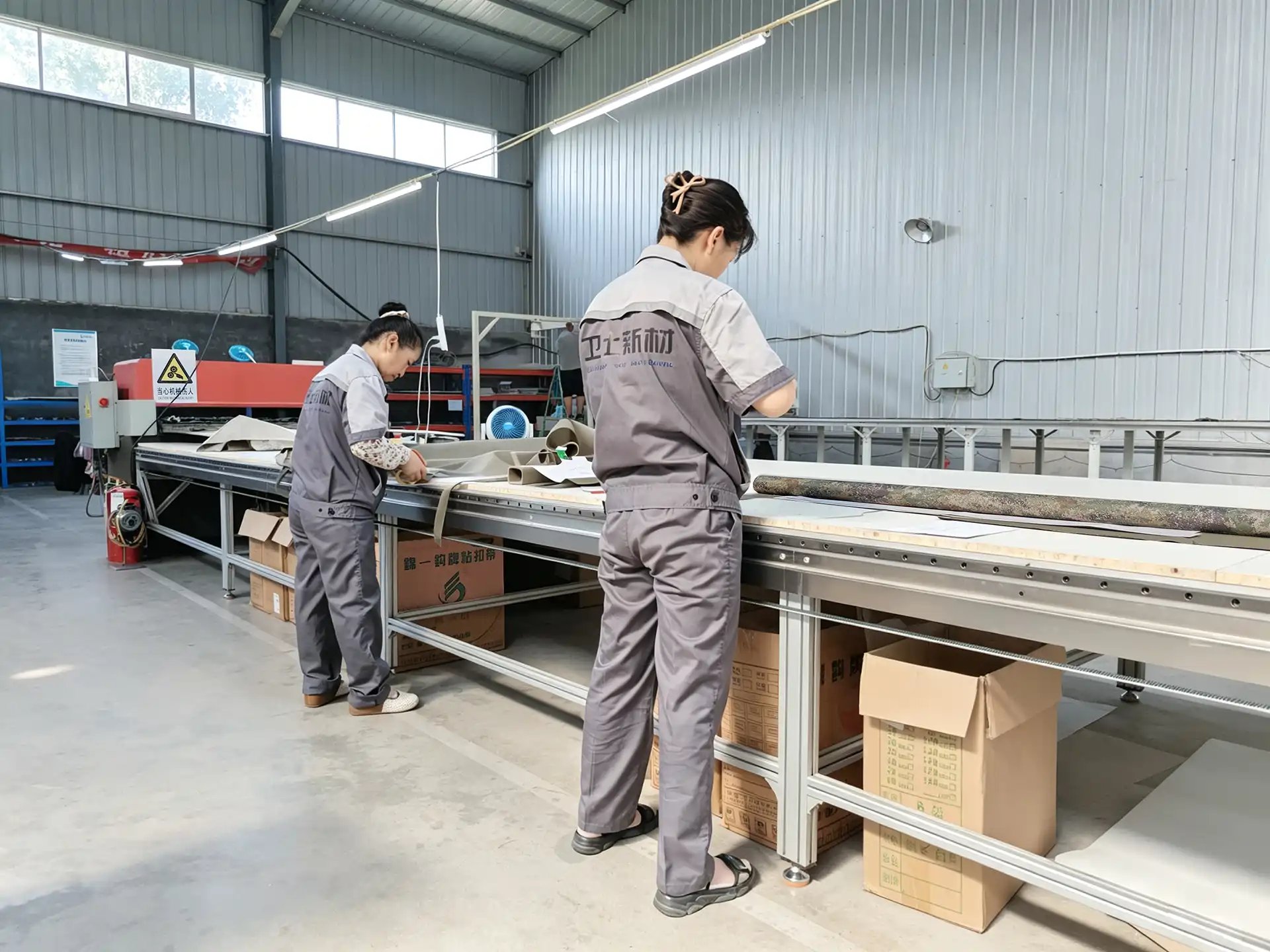 Workers preparing textile material on a long production table
