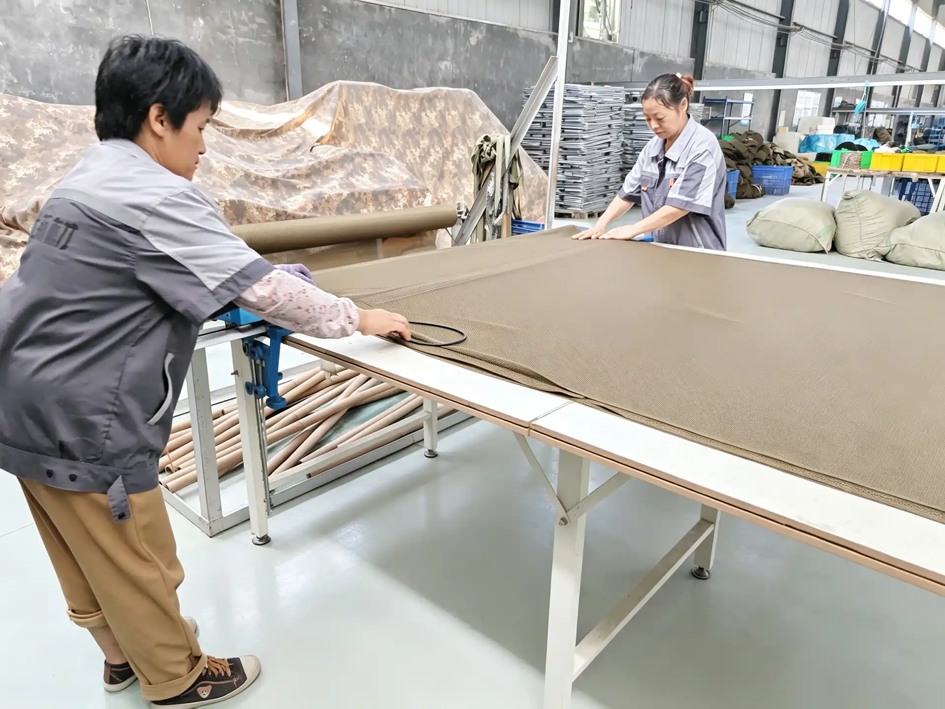 Workers measuring brown technical fabric on a long cutting table