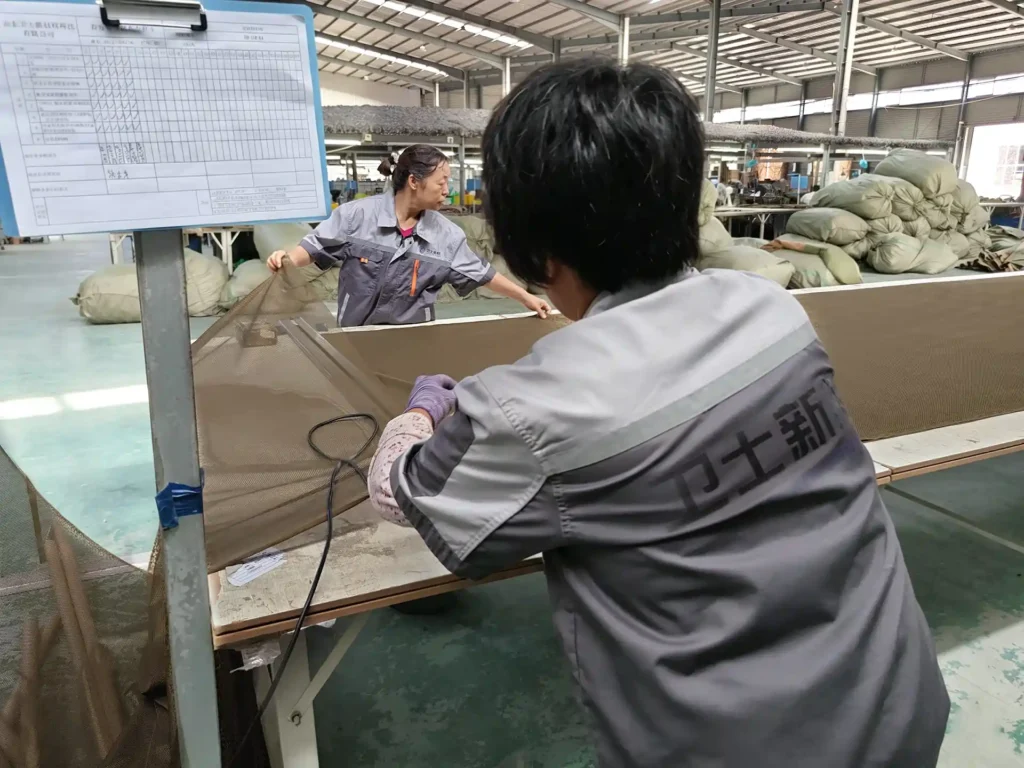 Worker inspecting technical fabric at a production workstation