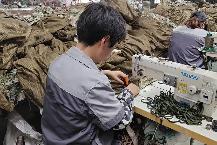 Factory worker sewing camouflage textile components